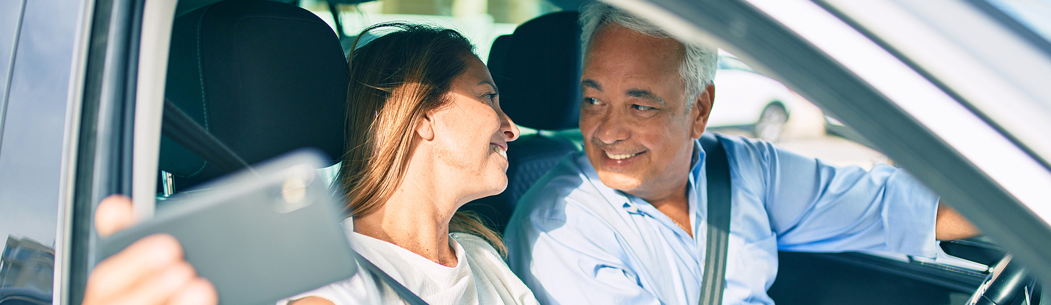 photo of a happy middle aged couple sitting in their car